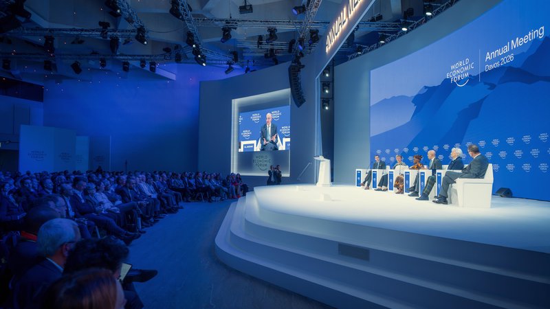 A wide auditorium view captures a panel discussion on the main stage before a large audience during the World Economic Forum in Davos, Switzerland.