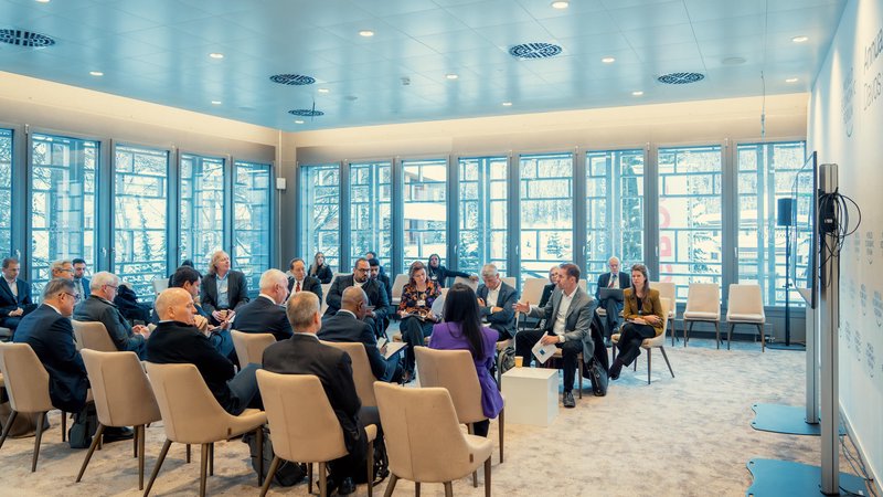 Business leaders exchange ideas in a bright, modern roundtable meeting during the World Economic Forum in Davos, Switzerland.