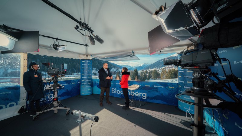 Broadcast cameras and crew frame an interview inside a Bloomberg studio overlooking the snowy Alps during the World Economic Forum in Davos, Switzerland.