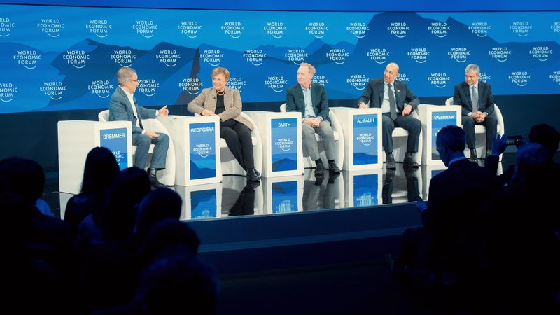 Panelists exchange views and smiles on a polished blue stage before an attentive audience during the World Economic Forum in Davos, Switzerland.
